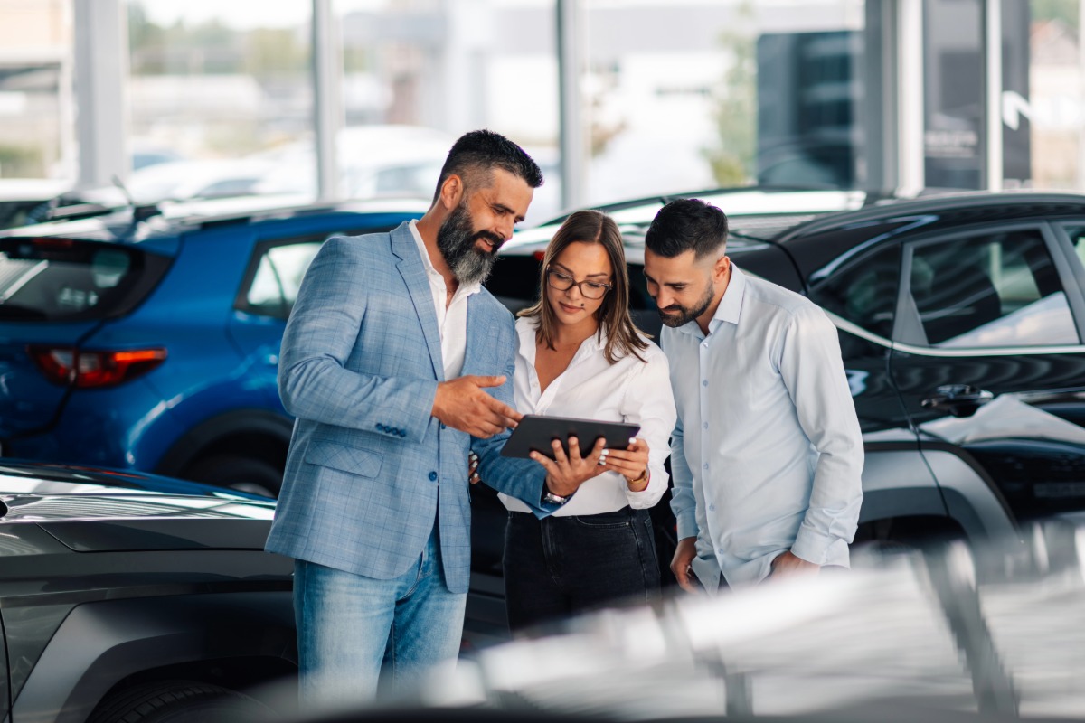 Verkaufsberater berät ein junges Paar im Autohaus