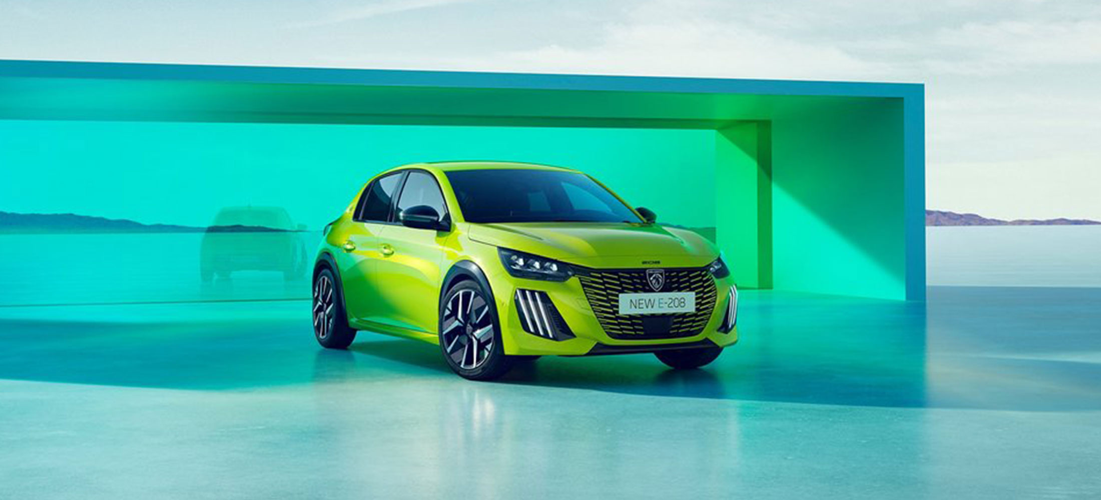 Für dieses Bild würde ich folgenden kurzen und barrierefreien Alt-Text verwenden: alt="Grüner Peugeot E-208 in schräger Frontansicht vor einer modernen türkisfarbenen Kulisse.