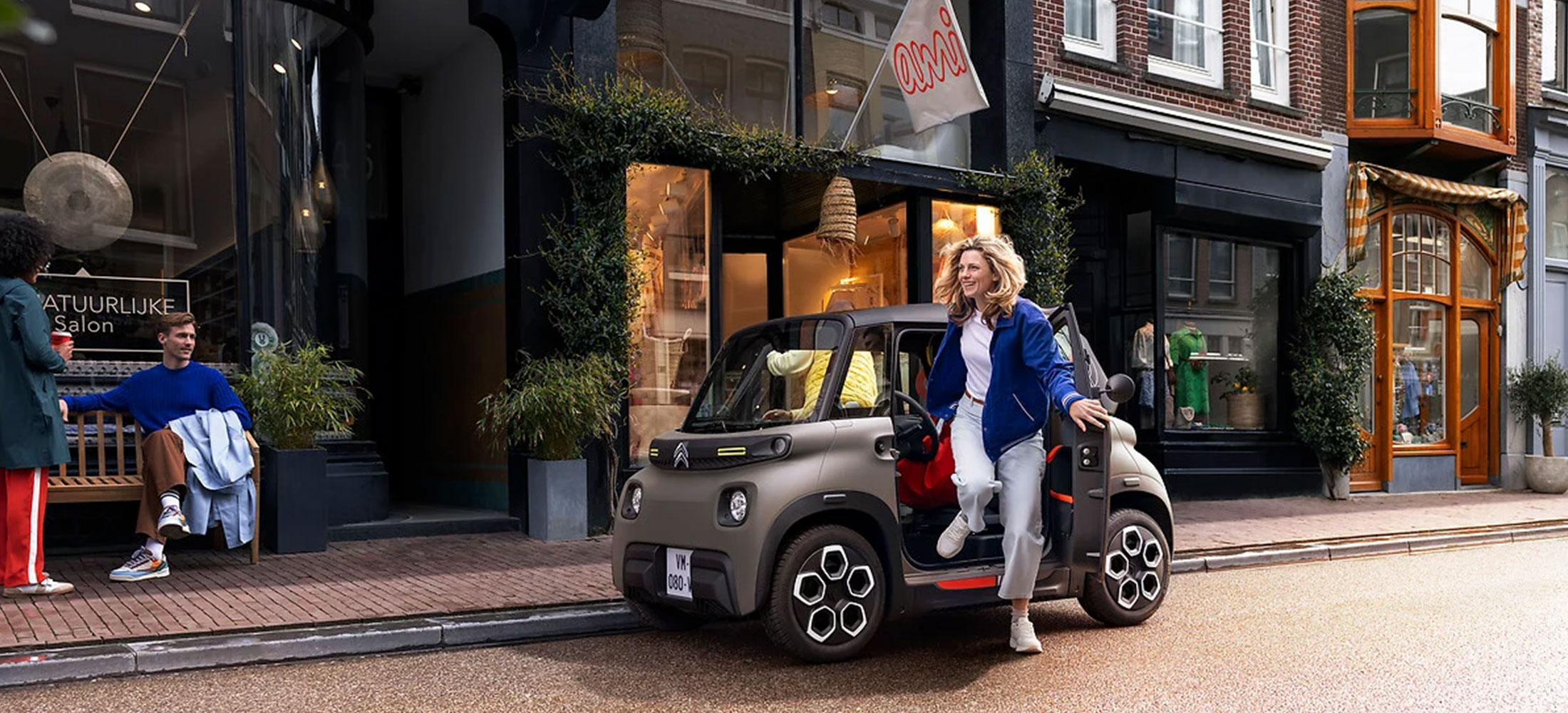 Citroen Ami geparkt an einer Straße, eine Frau steigt aus