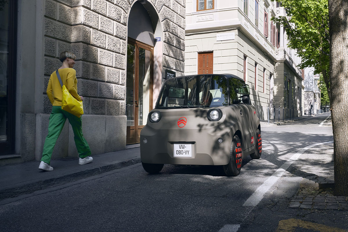Citroen Ami am Straßenrand, eine Frau läuft vorbei