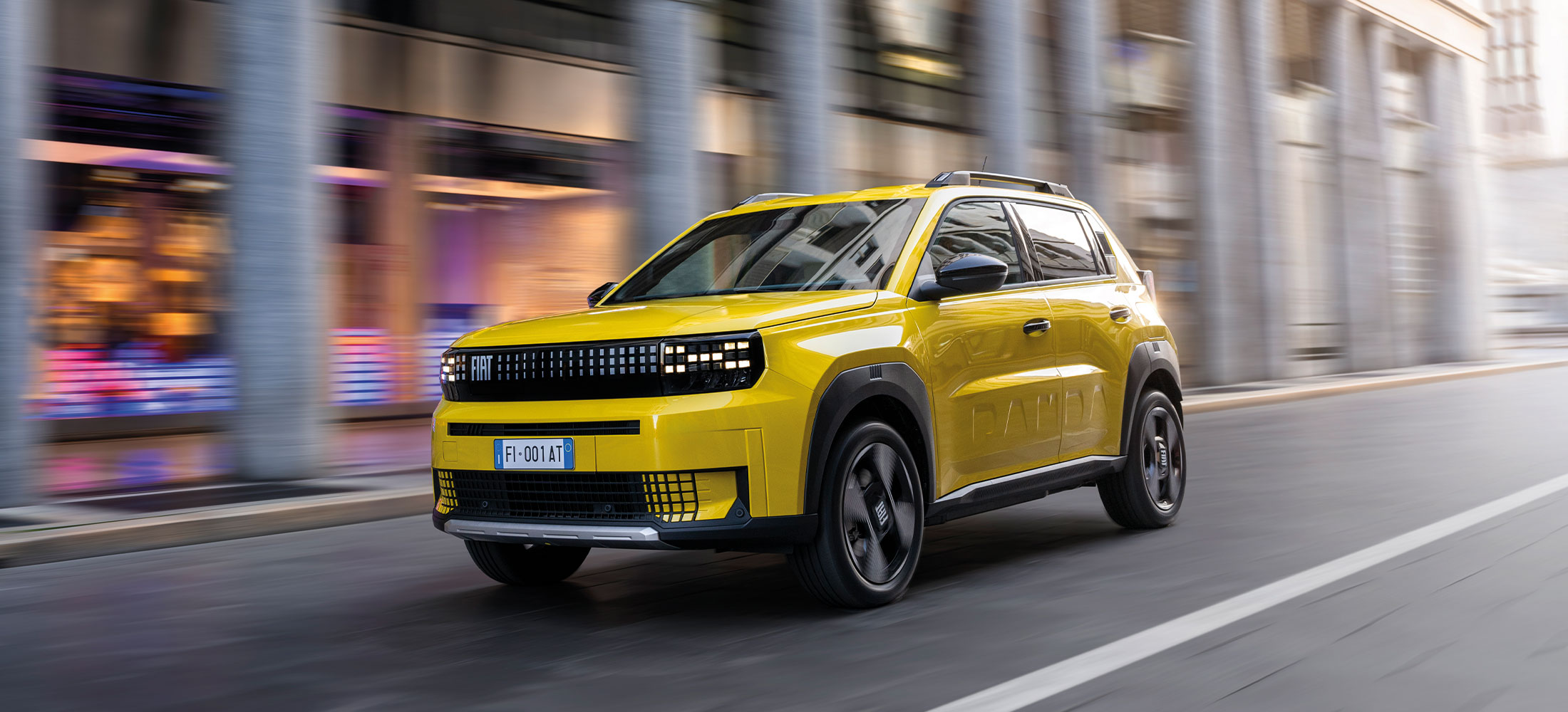 Fiat Grande Panda La Prima Elektro in Limone Gelb fahrend auf einer Straße