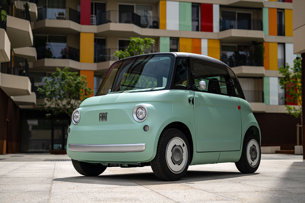 Fiat Topolino in hellblau fahrend in einer Gasse