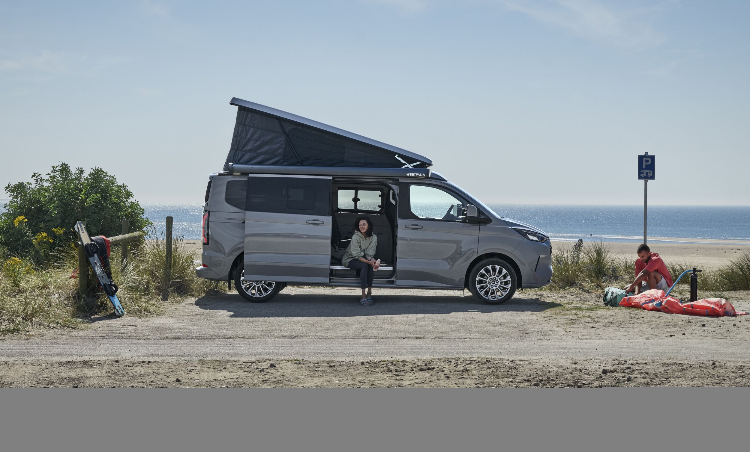Grauer Ford Nugget L2 mit aufgestelltem Aufstelldach und offener Tür