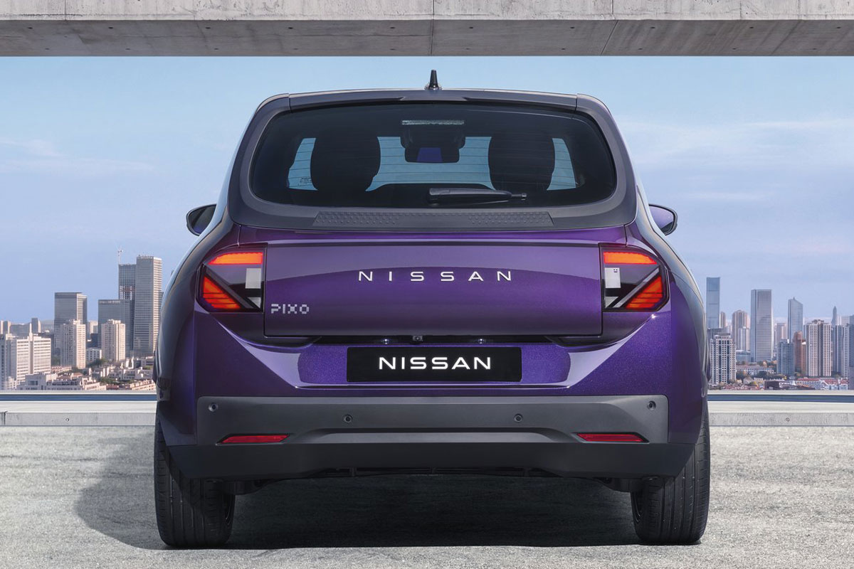 Violetter Nissan Pixo in Heckansicht vor einer modernen Stadtkulisse.