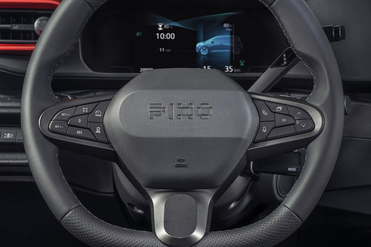 Detailansicht des Lenkrads im Nissan Pixo mit Bedientasten und digitaler Instrumentenanzeige.