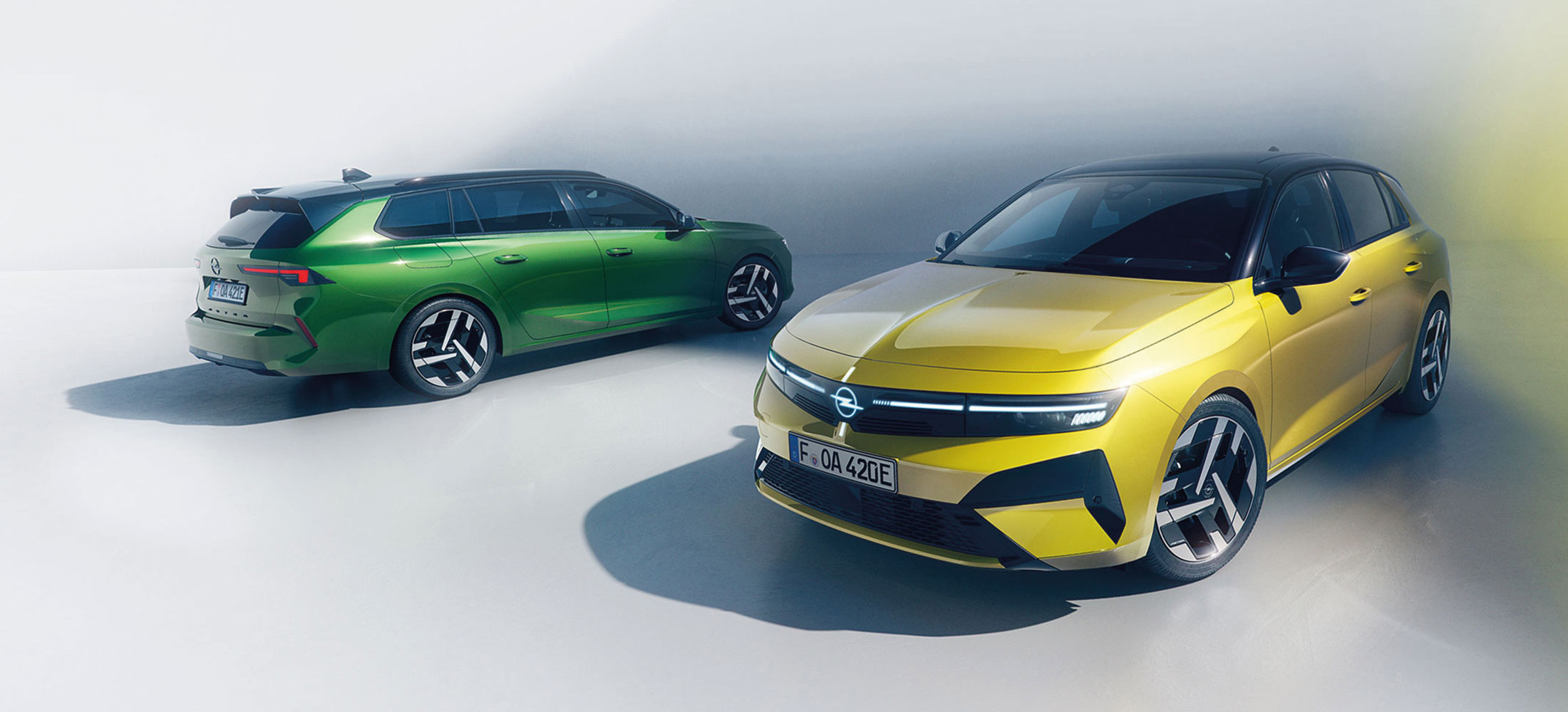 Gelber Opel Astra und grüner Opel Astra Sports Tourer in einer modernen, hellen Studiokulisse.