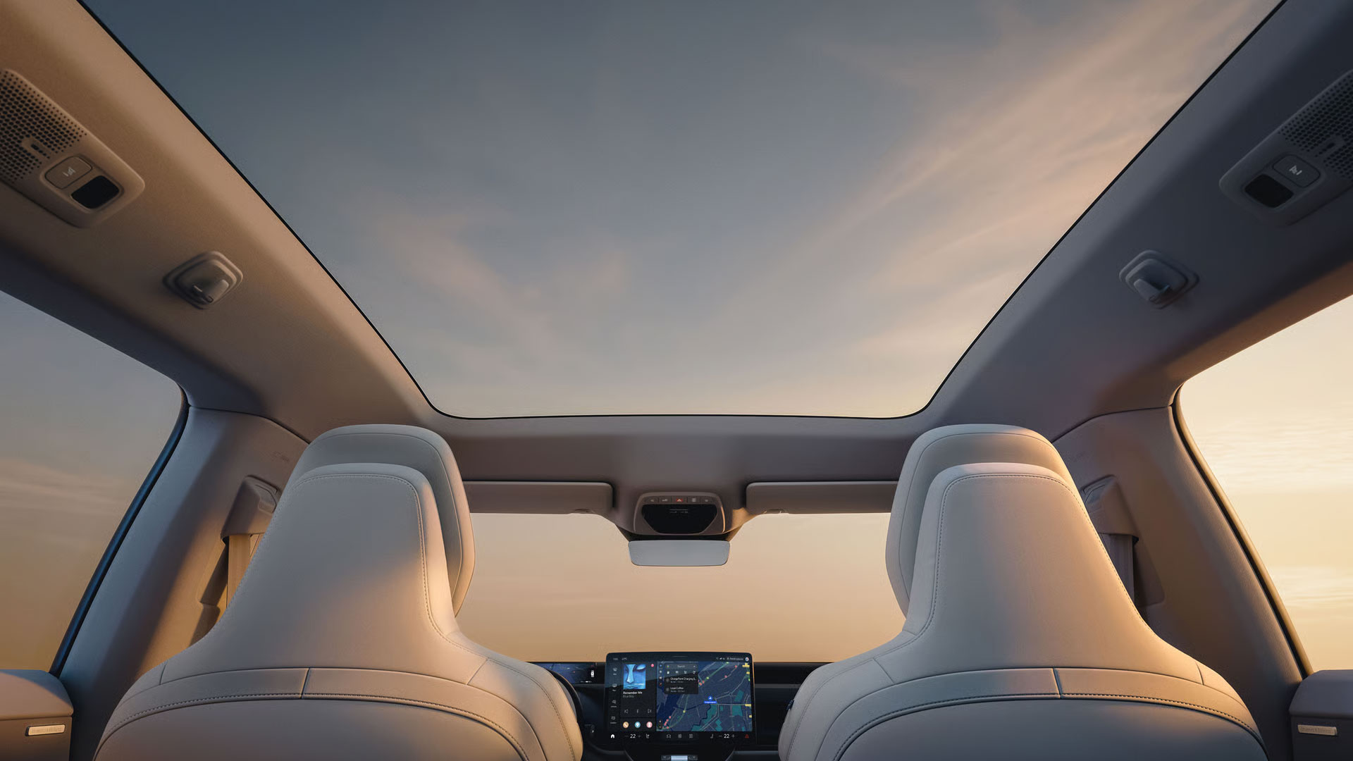 Ein Blick von den Rücksitzen des Volvo EX60 auf die Vordersitze, das mittlere Display und das Panoramadach