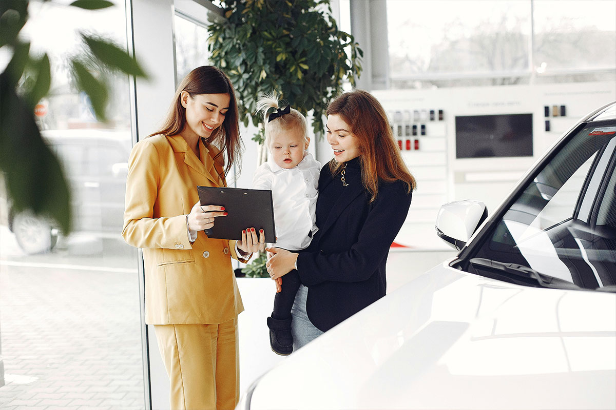 Fahrzeugfinanzierung im Autohaus mit 2 Frauen und einem Kind